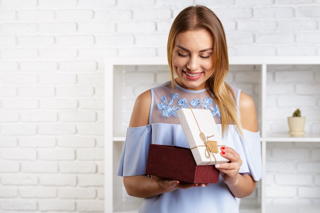 Glückliche recht junge Frau, die Geschenkbox hält