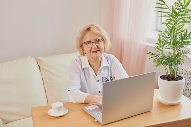 Glückliche reife ältere Frau mittleren Alters, die gute Nachrichten liest und auf den Laptop schaut