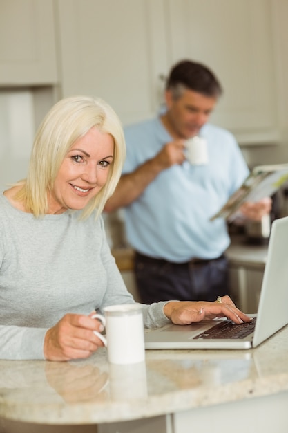 Glückliche reife Blondine, die Laptop verwendet