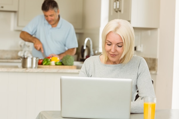 Glückliche reife Blondine, die Laptop verwendet