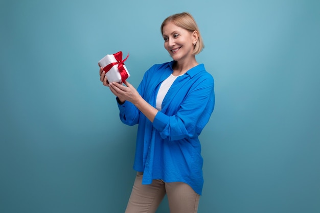 Glückliche reife Frau, die Bonusgeschenk auf blauem Hintergrundkopienraum hält