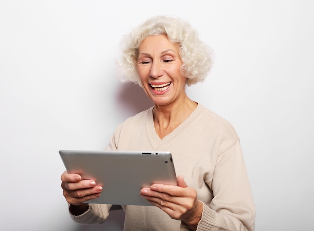 Glückliche reife Frau, die ein Tablet verwendet, kommuniziert mit Kindern und Enkelkindern