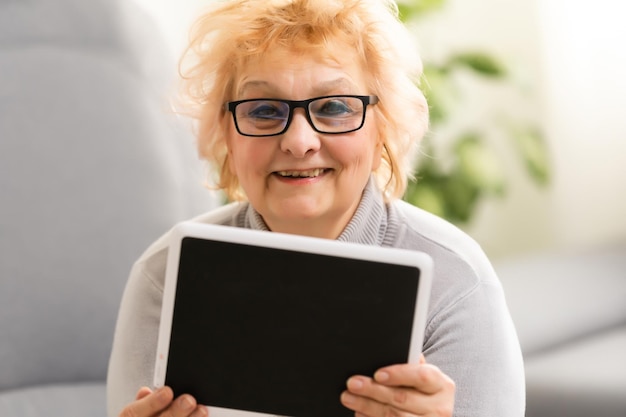 Glückliche reife Frau, die eine Tablette verwendet.