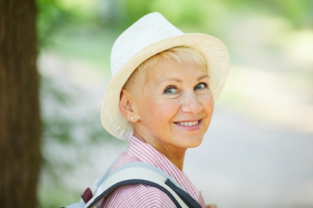 Glückliche reife Frau im Hut draußen