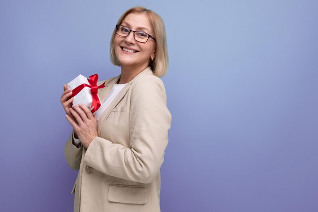 Glückliche reife Frau in Jacke erhielt Weihnachtsgeschenk auf Studiohintergrund mit Kopierraum