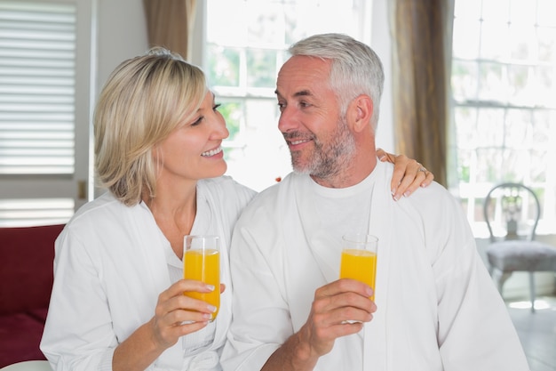 Glückliche reife Paare, die Orangensäfte halten