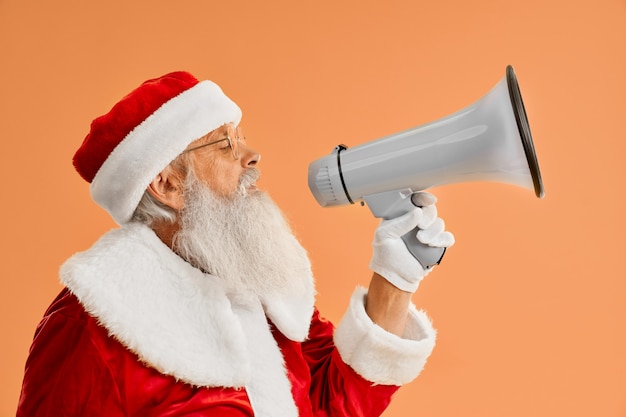 Glückliche reife Santa Claus, die im Megaphon im Studio spricht