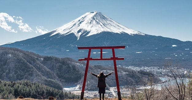 Glückliche reisende Frau zeigen Arme über Kopf am Fuji-Berg auf Hintergrund