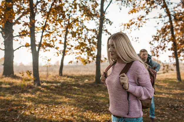 Glückliche Reisende mit Rucksäcken beginnen ihre Reise im herbstlichen sonnigen Wald