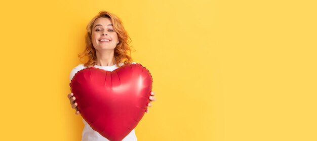 Glückliche rothaarige Dame mit romantischem Geschenk eines Partyballons, glücklicher Valentinstag. Schöne Frau