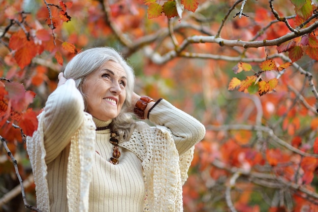 Glückliche schöne ältere Frau posiert im Herbstpark