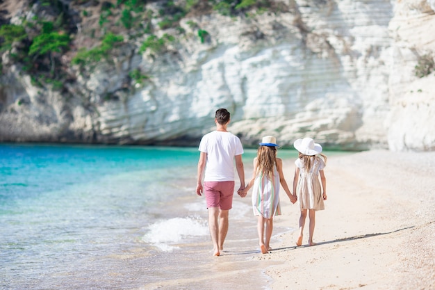 Glückliche schöne Familie des Vatis und der Kinder auf weißem Strand