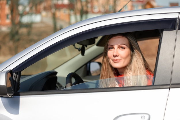 Glückliche schöne Frau, die aus einem fahrenden Auto schaut