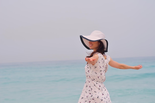 Glückliche schöne Frau, die Sommerferien am Strand genießt