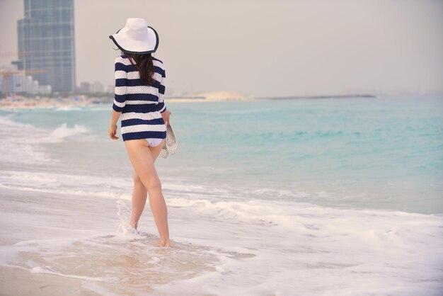 Glückliche schöne Frau, die Sommerferien am Strand genießt