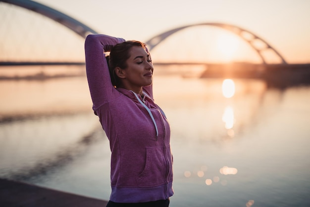 Glückliche schöne Joggerin, die neben dem Fluss trainiert.