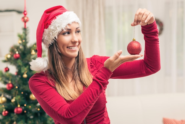 Glückliche schöne junge Frau, die rote Weihnachtsverzierung hält