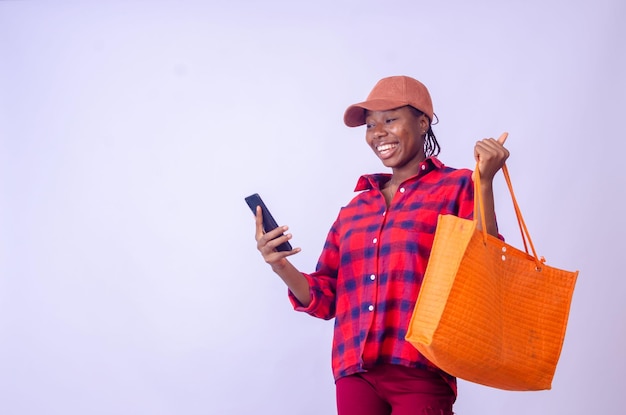 Glückliche schöne junge stilvolle Frau mit Einkaufstüten benutzt Smartphone