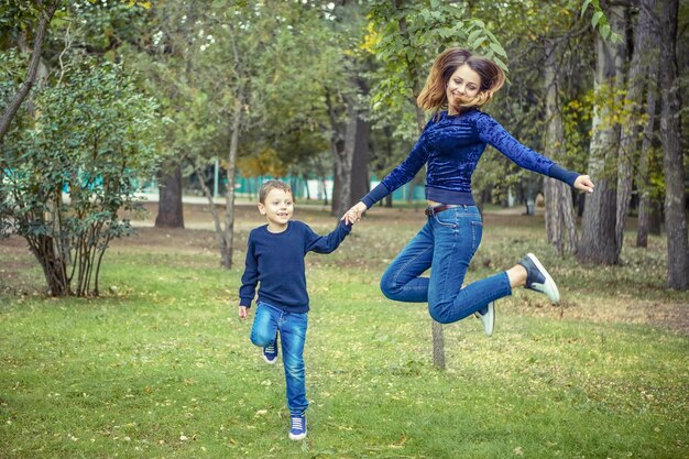 Glückliche schöne Mutter und Sohn, die das Springen genießen