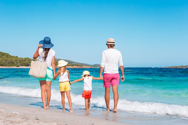 Glückliche schöne vierköpfige Familie auf weißem Strand