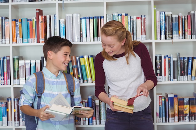 Glückliche Schüler, die Bücher in der Bibliothek lesen