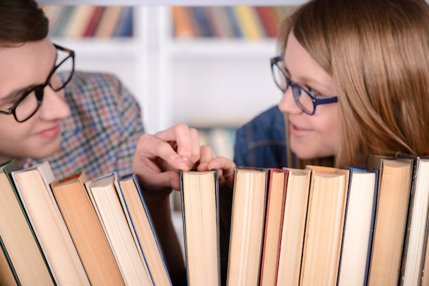 Foto glückliche schüler suchen buch zum lesen in der bibliothek.