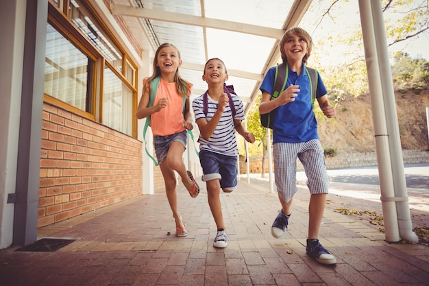 Glückliche Schulkinder, die in Korridor laufen