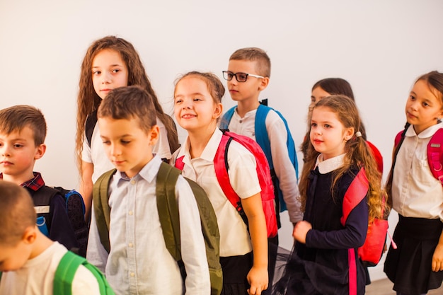 Glückliche Schulkinder sind bereit für die Bildung Schulkinder in Uniform mit Rucksäcken, die zum Unterricht gehen Zurück zum Schulkonzept