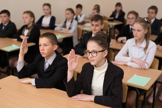 Glückliche Schulkinder sitzen an einem Schreibtisch im Klassenzimmer