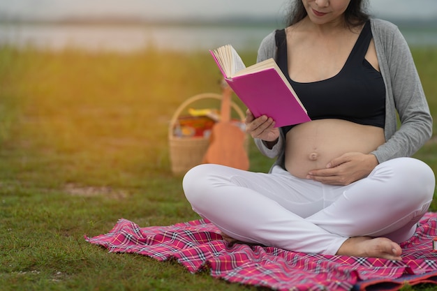 Glückliche schwangere Frau berührt ihren Bauch auf Blau