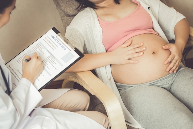 Glückliche schwangere Frau besucht Gynäkologen im Krankenhaus oder in der Klinik für Schwangerschaftsberater.