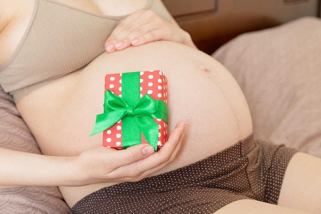 Glückliche schwangere Frau, die Weihnachtsgeschenkbox in ihren Händen hält Konzept des neuen Jahres