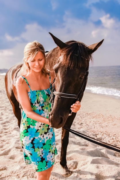 Glückliche schwangere Frau mit einem Pferd am Strand im Sommer in der Natur