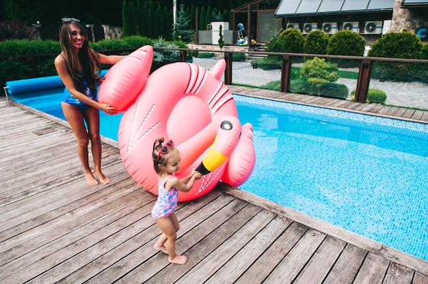 glückliche schwangere Frau und ihre kleine Tochter, die auf sunbed sich entspannt