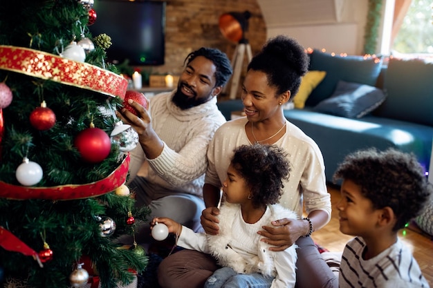 Glückliche schwarze Familie, die Weihnachtsbaum im Wohnzimmer schmückt
