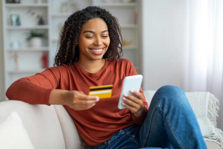 Foto glückliche schwarze frau macht mit smartphone und kreditkarte zu hause online-shopping