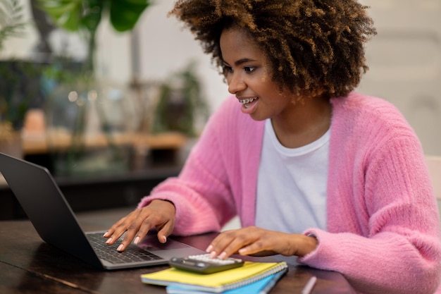 Glückliche schwarze Freiberuflerin, die von zu Hause aus mit einem Laptop-Rechner arbeitet