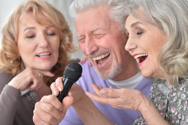 Glückliche Senioren, die Karaoke mit Laptop singen, während sie Tee trinken