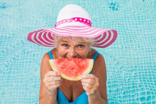 Glückliche Seniorin, die Party im Pool hat - Schöne Seniorin, die sich im Sommer in einem privaten Pool sonnen und entspannen kann
