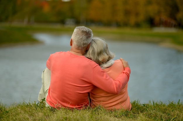 Glückliche Seniorin und Mann im Park sitzen am Teich