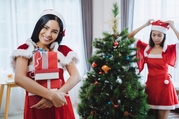 Glückliche sexy Sankt-Frau, die mit Weihnachtsgeschenkbox im Haus lächelt.