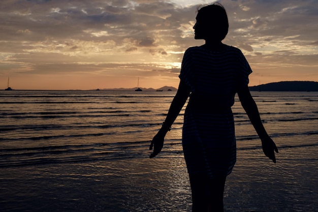Glückliche sorglose Frau, die schönen Sonnenuntergang auf dem Strand genießt