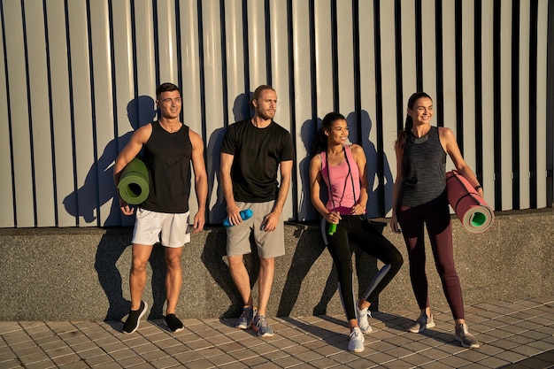 Glückliche Sportfreunde posieren in der Nähe der Wand im Freien