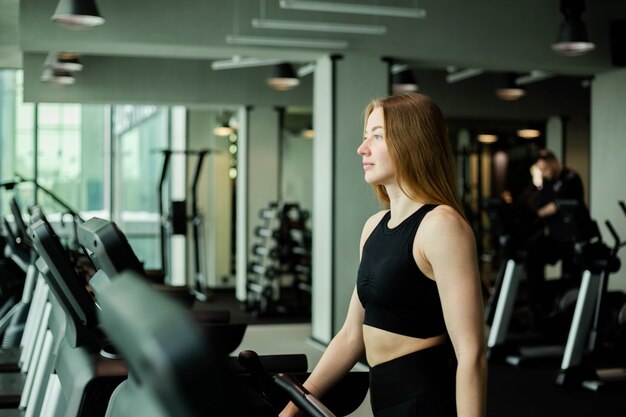 Glückliche sportliche Frau, die auf Laufbändern in einem Fitnessstudio joggt