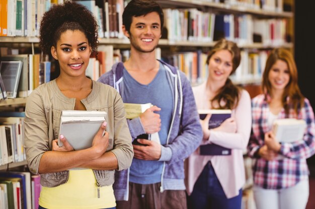 Glückliche Studenten, die Bücher in der Reihe halten