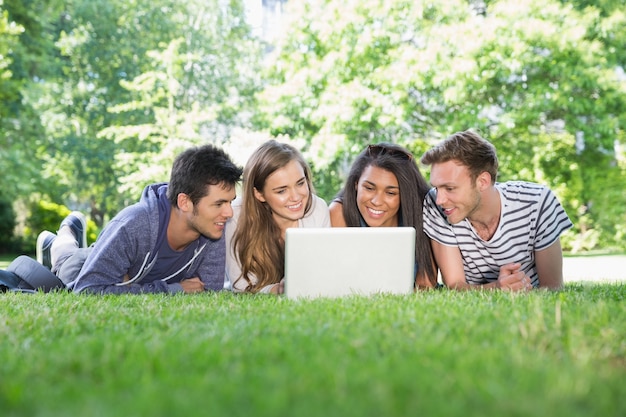 Glückliche Studenten, die draußen Laptop verwenden