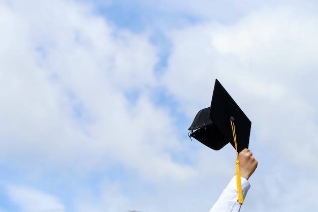 glückliche Studenten in Kleidern feiern ihren Abschluss und werfen die Hände in die Luft