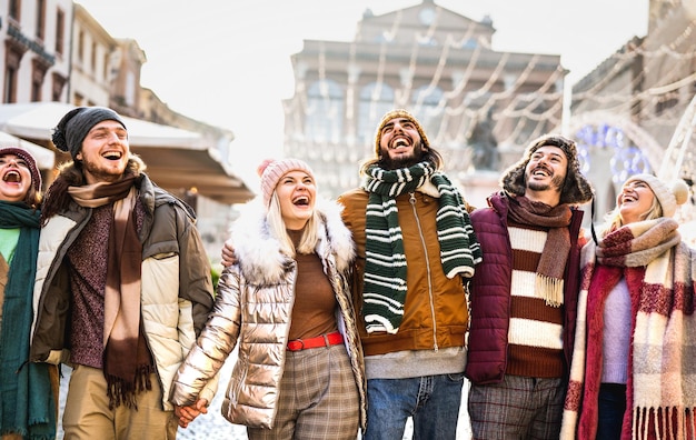 Foto glückliche studentengruppe, die an einem sonnigen wintertag in der europäischen stadt spazieren geht