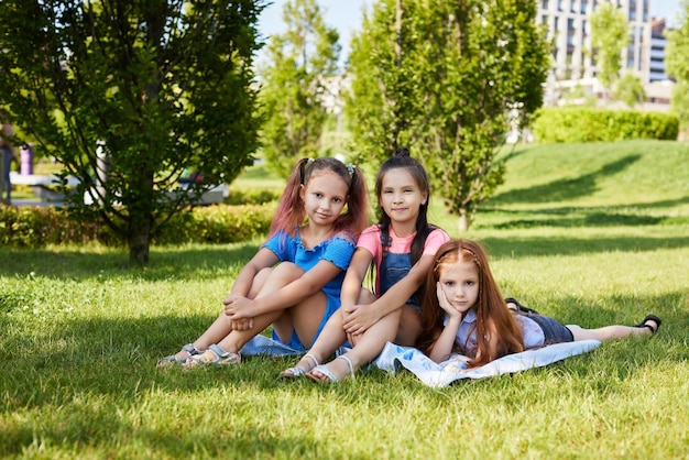 Glückliche süße Kindermädchen, die an einem sonnigen Sommertag zusammen im Park auf Gras spielen. Freundschaft und Kindheit