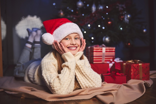 Glückliche Teenager-Frau, die sich in der Nähe von Weihnachtsbaum drinnen entspannt?